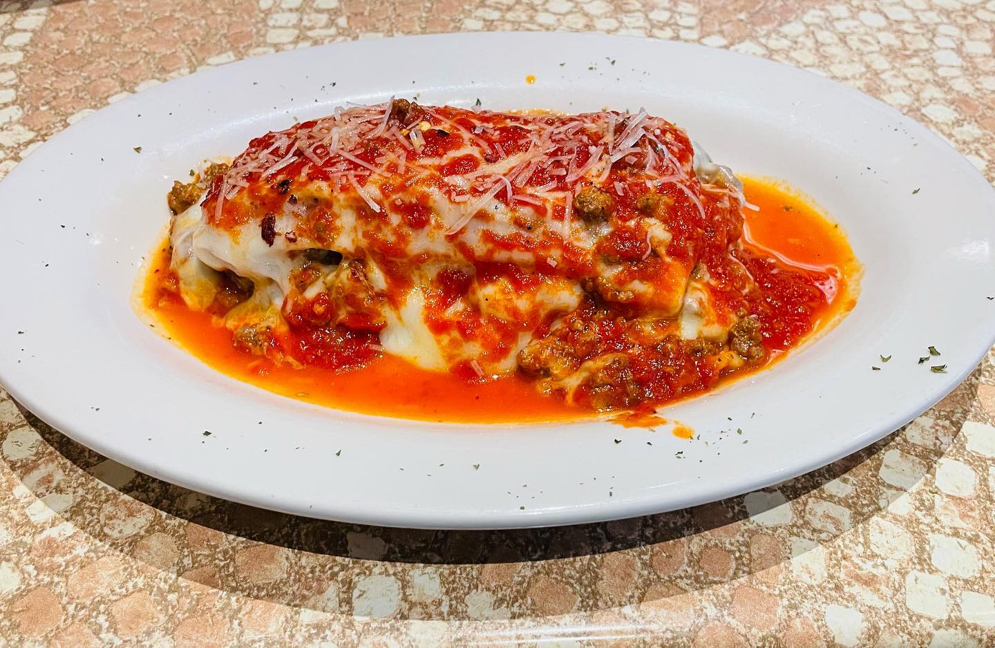 A plate of lasagna on a table with sauce on it.